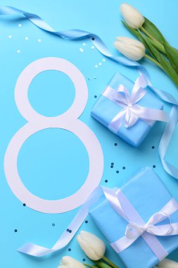 Hediye kutuları ve mavi arka planda güzel laleleri olan 8 numara. Uluslararası Kadınlar Günü