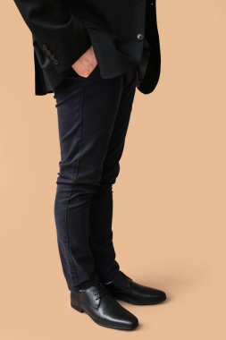 Kahverengi arka planda siyah şık ayakkabılı genç adam.