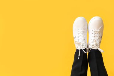Sarı arka planda beyaz renkli spor ayakkabılı genç adam bacakları.
