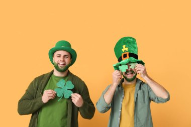 Yeşil sakallı cüce şapkalı genç adamlar sarı arka planda yonca tutuyorlar. Aziz Patrick Günü kutlaması