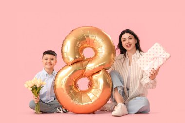 Küçük oğlu lale, hediye ve hava balonu tutan güzel bir kadın. Pembe arka planda 8 figürü var. Uluslararası Kadınlar Günü