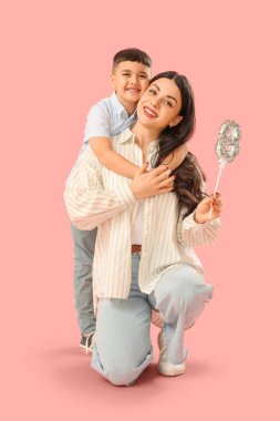 Güzel bir kadın ve küçük oğlu pembe arka planda 8 beden balon tutuyor. Uluslararası Kadınlar Günü