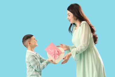 Sevimli küçük çocuk mavi arka planda Uluslararası Kadınlar Günü 'yle annesini selamlıyor.