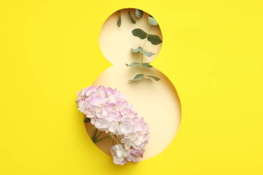 Sarı arka planda güzel bir ortanca çiçeği olan figür 8 şeklinde kesilmiş kağıt. Uluslararası Kadınlar Günü