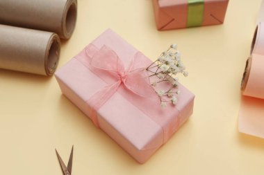 Paket kağıtlı hediye kutusu ve sarı arka planda çingene çiçekleri. Uluslararası Kadınlar Günü