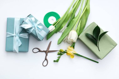 Beyaz zemin üzerinde güzel laleler ve makas olan hediye kutuları. Uluslararası Kadınlar Günü