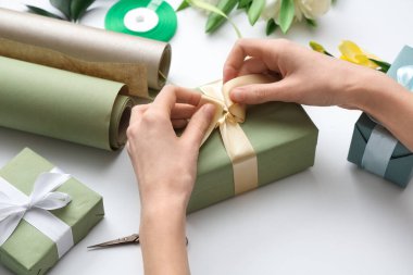 Hediye kutularıyla kadın elleri, ambalaj kağıdı ve beyaz arka planda güzel çiçekler. Uluslararası Kadınlar Günü