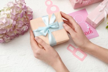 Hediye kutularıyla kadın elleri, kağıttan yapılmış 8 figür ve beyaz arka planda güzel ortanca çiçekleri. Uluslararası Kadınlar Günü