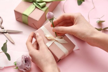 Hediye kutularıyla kadın elleri, güzel güller ve pembe arka planda ambalaj kağıtları. Uluslararası Kadınlar Günü