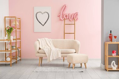 Beyaz kanepeli şenlikli oturma odasının içi, Sevgililer Günü kutlamaları için balonlardan ve dekorasyonlardan yapılmış aşk sözcüğü.