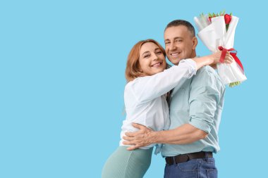 Mavi arka planda çiçek demeti olan orta yaşlı bir çift. Uluslararası Kadınlar Günü