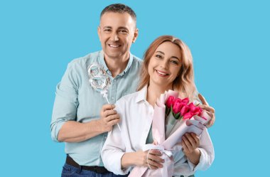Mavi arka planda şekil 8 şeklinde balon ve buketi olan orta yaşlı bir çift. Uluslararası Kadınlar Günü