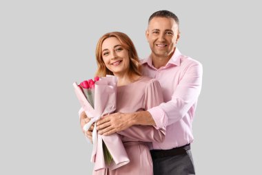 Gri arka planda çiçek demeti olan orta yaşlı bir çift. Uluslararası Kadınlar Günü