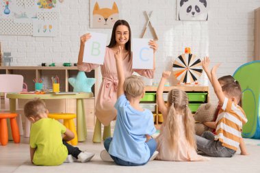 Anaokulunda anaokulu öğretmeni olan küçük çocuklar harf öğreniyor.