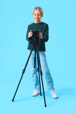 Mavi arka planda kamerası olan genç blogcu