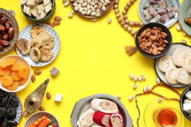 Sarı arka planda farklı Doğu tatlıları, Aladdin lambası ve Ramazan için tasbih çerçevesi