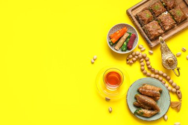 Sarı arka planda geleneksel Doğu tatlıları, Aladdin lambası ve Ramazan için tasbih kompozisyonu