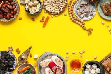 Sarı arka planda Ramazan için farklı Doğu tatlıları, tasbih ve Aladdin lambaları kompozisyonu