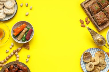 Sarı arka planda geleneksel Doğu tatlıları, Aladdin lambası ve Ramazan için tasbih kompozisyonu