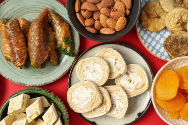 Kırmızı arka planda Ramazan için farklı Doğu tatlıları olan tabaklar, yakın plan
