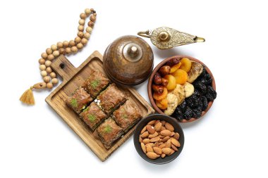 Beyaz arka planda geleneksel Doğu tatlıları, Aladdin lambası ve Ramazan için tasbih kompozisyonu