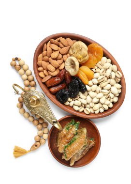 Beyaz arka planda lezzetli Doğu tatlıları, Aladdin lambası ve Ramazan için tasbih tabakları