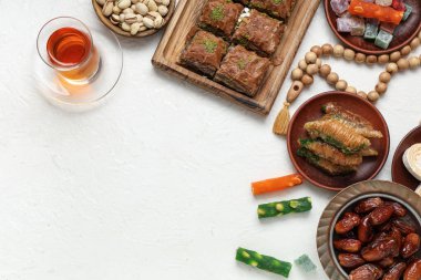 Geleneksel Doğu tatlıları ile kompozisyon, hafif arkaplanda Ramazan için tasbih çayı