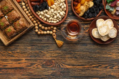 Ahşap zemin üzerinde geleneksel Doğu tatlıları, çay ve Ramazan için tasbih kompozisyonu