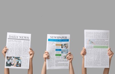 Gri arka planda gazeteleri olan kadınlar