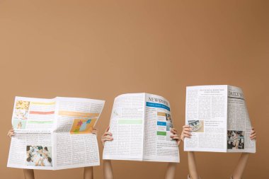 Kahverengi arka planda gazeteleri olan kadınlar