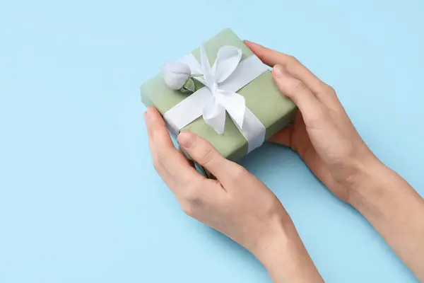 Weibliche Hände Mit Geschenkverpackung Und Wunderschöner Rose Auf Blauem Hintergrund — Stockfoto