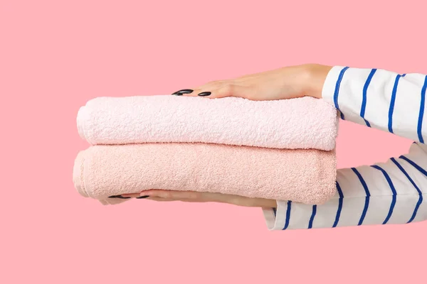 Female hands with clean towels on pink background