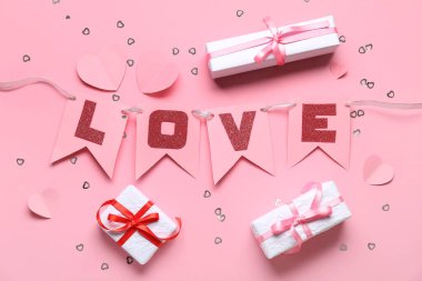 Sevgi kelimesi ve pembe arka planda hediye kutuları olan kağıt bayraklardan yapılmış bir çelenk. Sevgililer Günü kutlaması