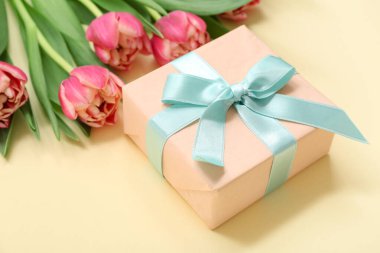 Hediye kutusu ve sarı arka planda güzel laleler. Uluslararası Kadınlar Günü