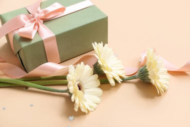 Güzel Gerbera çiçekleriyle hediye kutusu ve bej arka planda kurdele. Uluslararası Kadınlar Günü