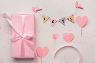 Beyaz arka planda Sevgililer Günü kutlaması için hediye kutusu, kelime aşkı ve kağıt kalp kompozisyonu