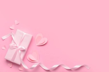 Pembe arka planda Sevgililer Günü kutlaması için hediye kutusu ve kağıt kalplerle kompozisyon