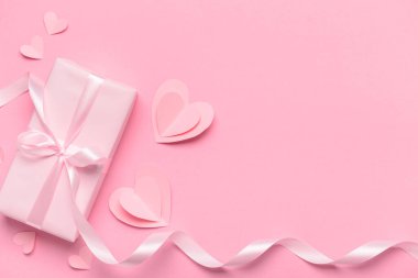 Pembe arka planda Sevgililer Günü kutlaması için hediye kutusu ve kağıt kalplerle kompozisyon
