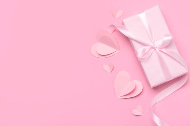 Pembe arka planda Sevgililer Günü kutlaması için hediye kutusu ve kağıt kalplerle kompozisyon