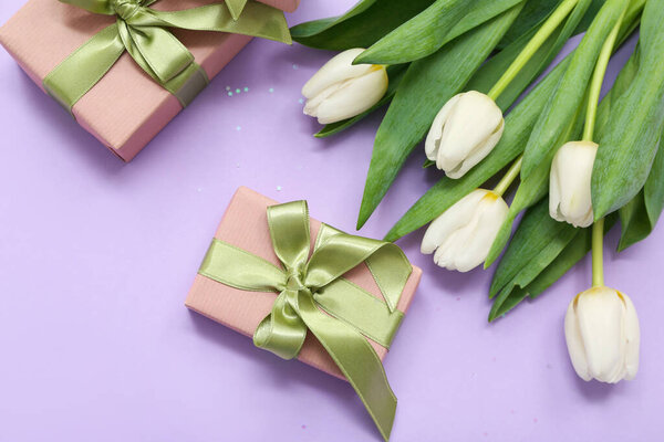 Gift boxes and bouquet of beautiful white tulips on lilac background. International Women's Day
