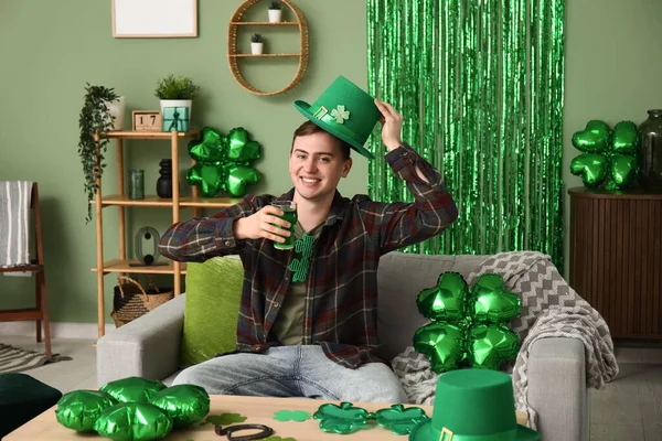Young man with beer at home on St. Patrick's Day