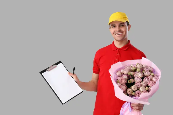 Male courier with bouquet of flowers and clipboard on light background
