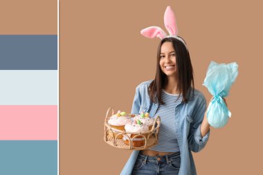 Tavşan kulaklı güzel bir bayan, Paskalya sepeti ve bej arka planda bir hediye. Farklı renk desenleri