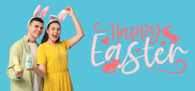 Tavşan kulaklı ve açık mavi arka planda oyuncakları olan mutlu bir çift. Paskalya bayrağı