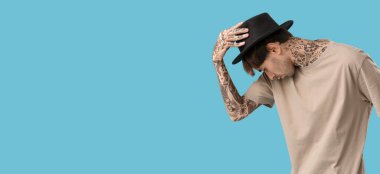 Açık mavi arkaplanda dans eden genç dövmeli adam metin için yer var