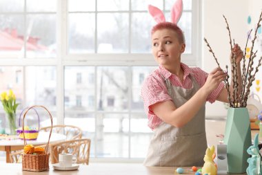 Tavşan kulaklı ve mutfakta söğüt dalları olan genç bir kadın.