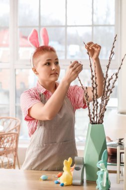 Tavşan kulaklı ve mutfakta söğüt dalları olan genç bir kadın.