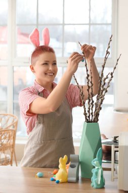 Tavşan kulaklı ve mutfakta söğüt dalları olan genç bir kadın.