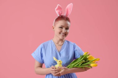 Tavşan kulaklı genç kadın, Paskalya tavşanı ve pembe arka planda laleler.