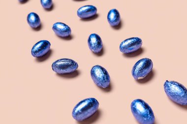 Renkli arka planda renkli folyo ile çikolatalı Paskalya yumurtaları, yakın plan.